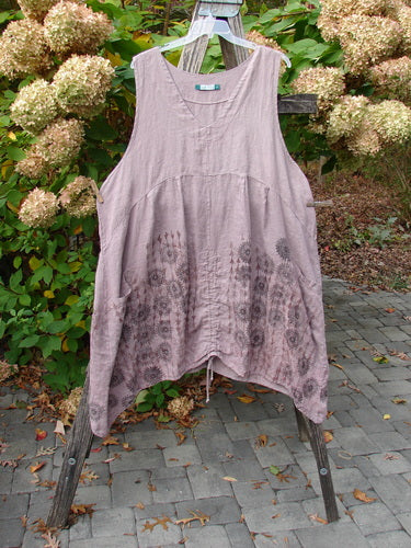 Barclay Linen Pleated Pocket Pinafore Mandala Soft Mauve Size 2, featuring a V-neck, deeper arm openings, and botanical motif, displayed on a stand, highlighting its artistic pleats and dual drawcords.