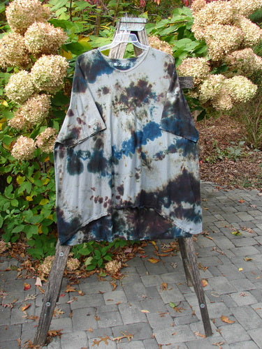 Barclay Drawcord Art Top Mottled Night Storm OSFA displayed on a small wooden ladder outdoors, highlighting its loose, A-line tunic shape, wide sleeves, and rounded neckline against a backdrop of hydrangeas.