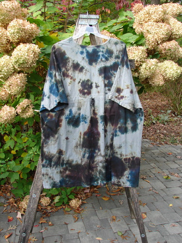 Barclay Drawcord Art Top Mottled Night Storm OSFA draped on a wooden hanger, showcasing its loose A-line shape, wide sleeves, rounded neckline, and varying hemline, set against a garden backdrop.