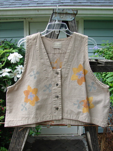 2000 Parachute Cross Stitch Vest Sunset Floral Dove 0 featuring a vibrant sunset floral pattern, deep V neckline, metal button closures, and a straight-edged bottom on a clothes hanger.