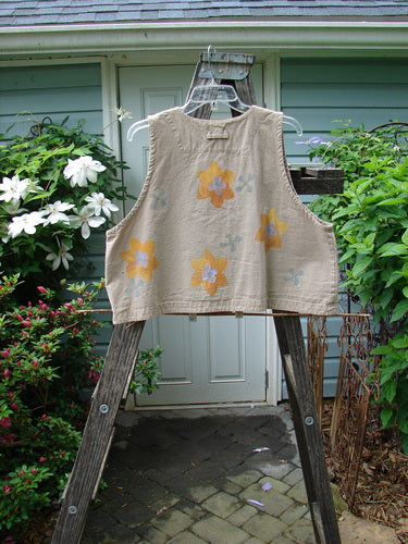 2000 Parachute Cross Stitch Vest Sunset Floral Dove 0 displayed outdoors, features deep V-neckline, four metal buttons, and bright floral pattern on tan fabric.