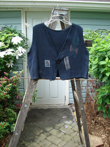 1995 Reprocessed Jazz Vest Mystery Gal Black Altered Size 2 displayed on a ladder, featuring a shorter back hemline, deep V neck, single button closure, and signature bright blue fish patch.