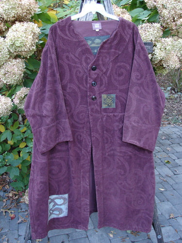 2000 Patched Upholstery Diwmach Coat Celtic Time Aubergine Size 2, showcases a textured damask swirl pattern, accented with colorful Celtic patches, vintage buttons, and belled sleeves, hanging outdoors against a garden backdrop.
