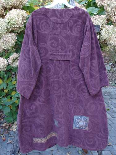 2000 Patched Upholstery Diwmach Coat Celtic Time Aubergine Size 2, with a swirling paisley pattern, decorative patches, scalloped neckline, vintage buttons, and belled sleeves, hangs outdoors on a porch railing.