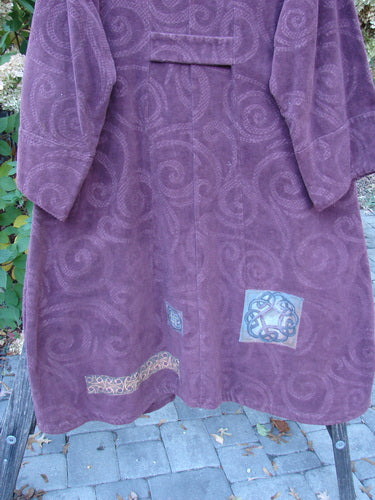 2000 Patched Upholstery Diwmach Coat Celtic Time Aubergine Size 2, featuring a knee-length suede-like fabric with spiral motifs, wide kimono sleeves, and Celtic-themed appliqués.
