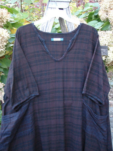 Barclay Flannel Keyhole Drawcord Pocket Dress Brum Plaid Size 2, featuring a loose fit, V-neck, elbow-length sleeves, and large side pockets, hanging outdoors amidst foliage.