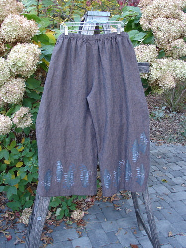 Barclay Cross Dye Linen Wide Leg Crop Pant in muted brown with a floral sphere theme, featuring wide, cropped legs and an elastic waistband, displayed on a wooden ladder outdoors.