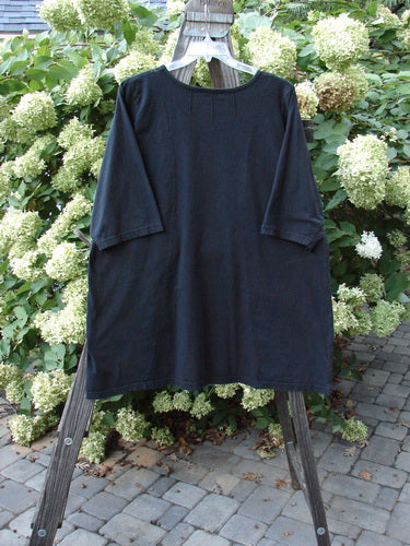 Barclay Sunrise Pin Tuck Pocket Tunic Unpainted Black Size 2 displayed on a wooden rack, showcasing its unique A-line shape and lower drop pockets.