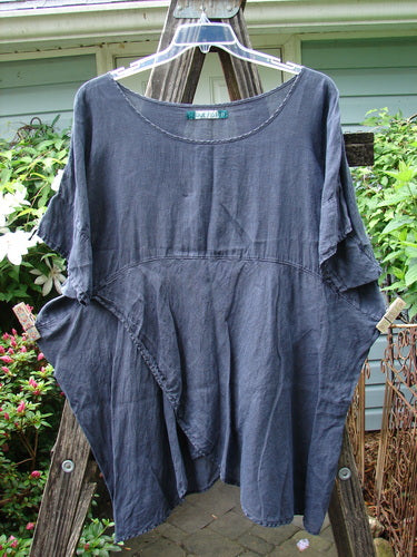 Barclay Linen Lower Wrap Tunic Top Unpainted Steel Navy Size 2 displayed on a wooden rack, showcasing its wider neckline, three-quarter sleeves, and unique sectional lower wrap.