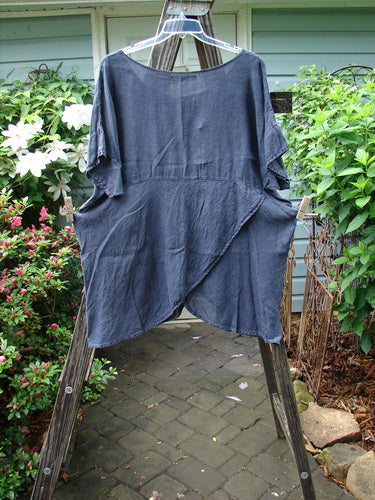 Barclay Linen Lower Wrap Tunic Top Unpainted Steel Navy Size 2 displayed on a wooden easel, showcasing its wider neckline, three-quarter sleeves, and unique sectional lower wrap design.