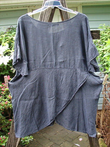 Barclay Linen Lower Wrap Tunic Top Unpainted Steel Navy Size 2, displayed on a clothesline, showcasing its wider neckline and three-quarter sleeves with a unique varying sectional lower wrap.