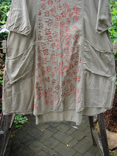 Barclay Batiste Bliss Dress Fallen Petal Stonetail Size 0 displayed on a clothesline, showcasing its soft rounded neckline, short sleeves, two exterior pockets, and unique falling petal design.