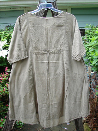 Barclay Batiste Bliss Dress Fallen Petal Stonetail Size 0 on rack, showcasing its soft rounded neckline, short sleeves, and drawcord back, highlighting the unique falling petal theme for creative expression.