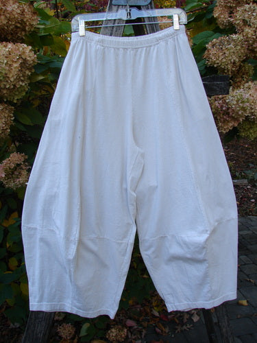 1999 4 Square Pant Unpainted Natural Size 1: Loose-fitting, knee-length white pants on a hanger, featuring an elastic waistband, dropped crotch, and unique 3D diamond cut from the knee down.