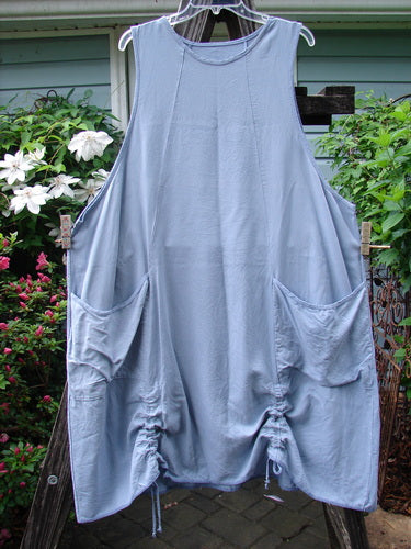 Barclay Lyocell Sectional Pocket Venetian Jumper Unpainted Sky Size 2 hanging on a clothesline, showcasing its unique figure-eight seams, widening lower, and drop front pockets, capturing the essence of vintage Blue Fish style.