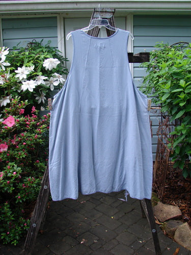 Barclay Lyocell Sectional Pocket Venetian Jumper Unpainted Sky Size 2 hanging on a clothes rack, showcasing unique curvy seams, exterior pockets, and an A-line shape.