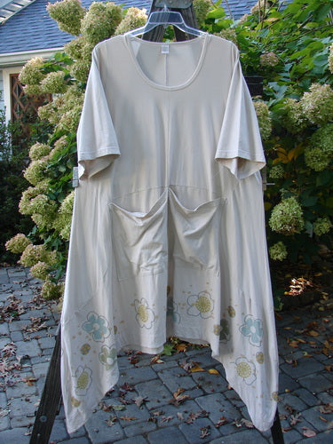 Barclay Cotton Lycra Double Pocket Bounce Tunic Dress Floral Creme Size 2, hanging on a clothesline, showcasing its oversized front pockets, curvy seams, and varying hemline.