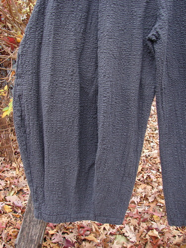 Barclay Pucker Crop Mojo Pant Unpainted Ironworks Size 1, draped over a wooden post, showcasing its unique 3D diamond cut from the knee down, with generous front pockets and a textured finish.