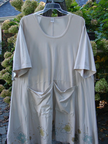 Barclay Cotton Lycra Double Pocket Bounce Tunic Dress Floral Creme Size 2, displayed on a clothes rack, featuring front pockets and a flowing hemline.