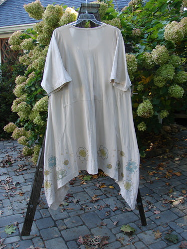 Barclay Cotton Lycra Double Pocket Bounce Tunic Dress Floral Creme Size 2 displayed on a rack, showcasing oversized front drop bushel pockets, curvy seams, and a festive floral garden design.