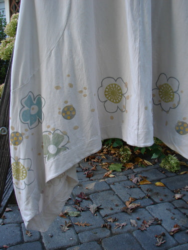 Barclay Cotton Lycra Double Pocket Bounce Tunic Dress Floral Creme Size 2, featuring oversized front pockets, curvy seams, and a distinctive hemline, adorned with a festive floral garden theme.