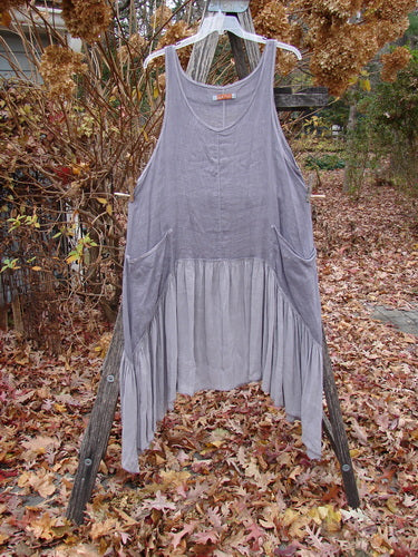 Barclay Gauze Silk Summer Frock Jumper Unpainted Grey Haze Size 1, featuring a sleeveless design, scoop neckline, asymmetrical hem, and side pockets, hangs on a ladder amidst autumn leaves.