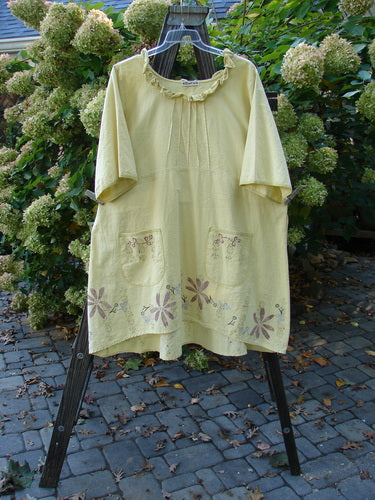 Barclay Linen Duet Sunrise Dress Roman Goddess Sunshine Size 2 on a rack, featuring curly neckline, puckered pleats, front pockets, floral and Roman Goddess design, with a varying hemline.