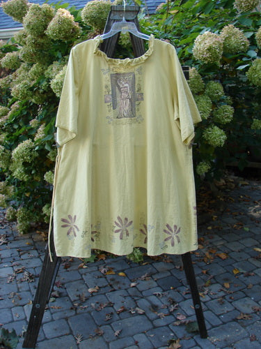 Barclay Linen Duet Sunrise Dress Roman Goddess Sunshine Size 2 on a rack, showcasing curly neckline, vertical pleats, front pockets, floral and goddess patterns, and a varying hemline in durable linen fabric.