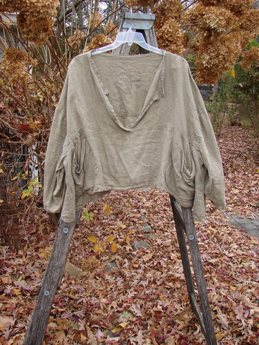 Magnolia Pearl Linen Crop Artist's Pocket Pullover Light Army OSFA displayed on a wooden ladder outdoors, featuring billowy sleeves, empire seams, and oval pockets amidst a backdrop of autumn leaves and dried hydrangeas.