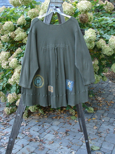 Barclay Patched Thermal Touring Cardigan Lucky Guy Pond Green OSFA displayed on a wooden rack, showcasing its flared hem, button line, deep V-neck, and kangaroo pocket.