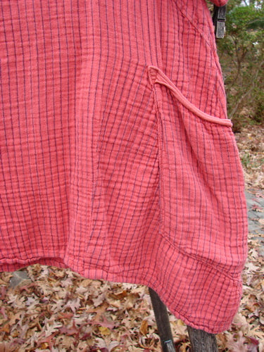 Barclay Gauze Two Pocket Urchin Dress in Unpainted Geranium Stripe Size 1 draped outdoors, showcasing its flutter neckline, unique A-line shape, three-quarter sleeves, and distinctive rounded side pocket above fallen leaves.