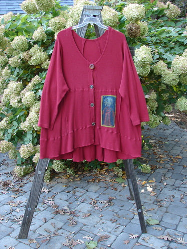 Barclay Patched Thermal Touring Cardigan Lucky Guy Ruby Red OSFA displayed on a wooden stand, showcasing a flared hem, deep V-neck with mixed buttons, and front kangaroo pocket.