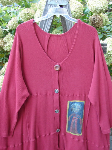 Barclay Patched Thermal Touring Cardigan Lucky Guy Ruby Red OSFA featuring a picture on the front, flared hem, mixed vintage buttons, and kangaroo pocket, displayed on a wooden surface.