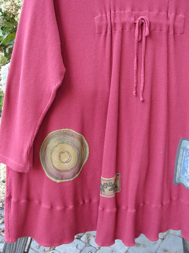 Close-up of Barclay Patched Thermal Touring Cardigan Lucky Guy Ruby Red OSFA, highlighting the unique flared hem, deep V-neck, vintage buttons, and drawcord back.