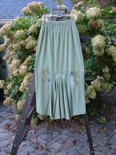 1995 Kick Pleat Skirt Road Less Traveled Spanish Moss Size 1: A skirt on a rack, featuring a full elastic waist, widening shape, and a sassy rear kick pleat.