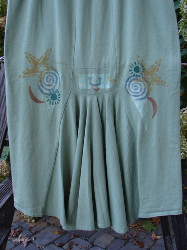 1995 Kick Pleat Skirt Road Less Traveled Spanish Moss Size 1: A green skirt with a design, featuring a full elastic waist, widening shape, sassy rear kick pleat, and painted accents on the waistband. Made from organic cotton.