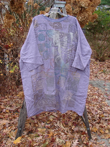 Barclay Linen Oversized Gallery Dress Home Fall Violet OSFA displayed on a wooden easel in a garden, featuring a knee-length, loose fit with abstract patchwork and sparkly studs, amid autumn leaves.