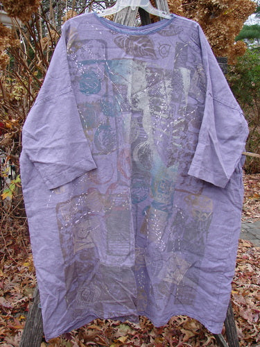 Barclay Linen Oversized Gallery Dress Home Fall Violet OSFA: A loose-fitting, knee-length tunic in pale lavender linen, featuring a patchwork design. Hanging on a wooden hanger, surrounded by dried hydrangeas. Ideal for creative expression.