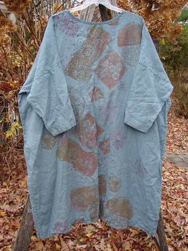 Barclay Linen Oversized Gallery Dress Falling Daisy Delaware OSFA, featuring a loose fit, rounded neckline, and three-quarter dolman sleeves, showcases a patchwork of floral and geometric prints on light blue/grey linen.