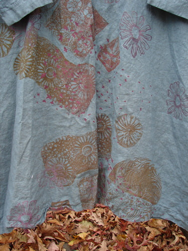 Barclay Linen Oversized Gallery Dress Falling Daisy Delaware OSFA with stylized floral and botanical motifs in muted tones, displayed with dried autumn leaves accentuating its elegant, flowy hem.