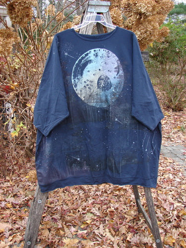 Barclay Cotton Lycra Flutter Hem Dolman Pullover Centered Ink OSFA draped on easel, showcasing a large, painted moon motif. Autumnal setting highlights the pullover's artistic design and unique, generous shape.