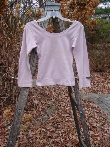 1994 Cotton Lycra Ballerina Layering Top Unpainted Plave Smaller Size 2 hangs on a wooden ladder, showcasing its scoop neck, long sleeves, and tapered waist, embodying Bluefishfinder.com's vintage style.