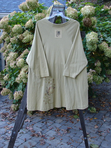 1998 Botanicals Bell Flower Top Root Berry Seed Size 2: A long-sleeved, belled A-line shirt with a scooped front hem, rounded neckline, and sectional panels, displayed on a rack.