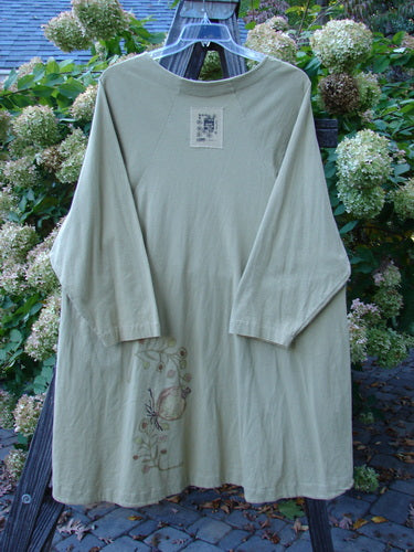1998 Botanicals Bell Flower Top Root Berry Seed Size 2 displayed on a hanger, featuring long sleeves, a softly rounded neckline, and a unique upward scooped front hemline with botanical-themed paint.