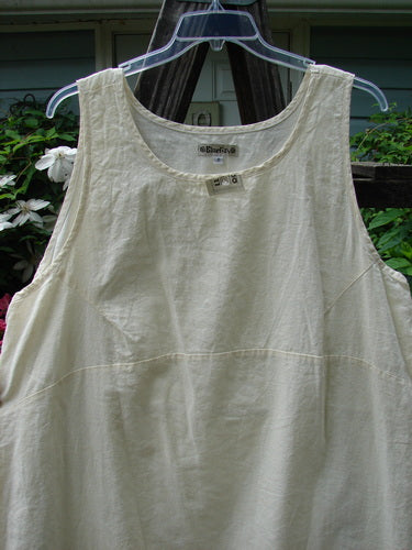 Barclay NWT Hemp Cotton Empire Flutter Pinafore Unpainted Creme Size 2 displayed on a hanger, showcasing its rounded neckline, asymmetrical hemline, and diagonal bust darts.