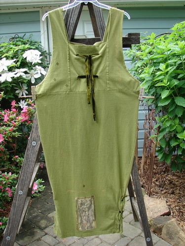 1993 Tie Jumper Mythical Goddess Olive Size 2 displayed on a wooden ladder, showcasing thick shoulder straps, empire waist, velvet ribbon ties, and painted hem with side vent.