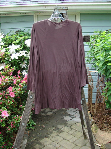 Barclay Batiste Tunic Curve Top Unpainted Red Earth Size 2 displayed on a wooden rack, showcasing curvy seams, longer sleeves, narrowing forearms, and a rounded neckline with curly edgings.