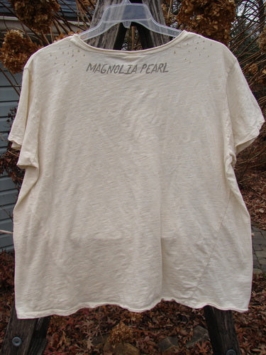 Magnolia Pearl NWT Cotton Jersey Boyfriend Tee Ganesh Moonlight OSFA, light-beige, with hand-lettered 'MAGNOLIA PEARL' on back, draped on a hanger outdoors, showcasing its super soft, drapey cotton jersey texture.