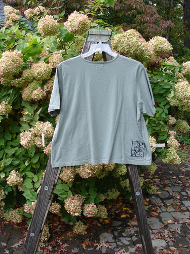 1999 Patched Short Sleeved Crop Tee Tri Floral Shale Size 2 displayed on a wooden rack, showcasing its classic 1999 tri floral theme patch and feminine rolled neckline.