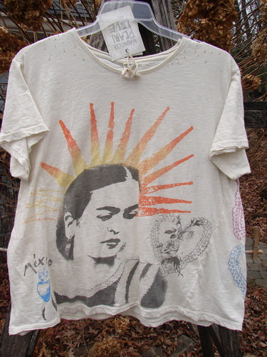 Magnolia Pearl NWT Cotton Jersey Boyfriend Tee Frida Del Sol True OSFA hangs on a wooden bench, featuring a stylized woman's face with sun rays and heart graphic, embodying creative expression.